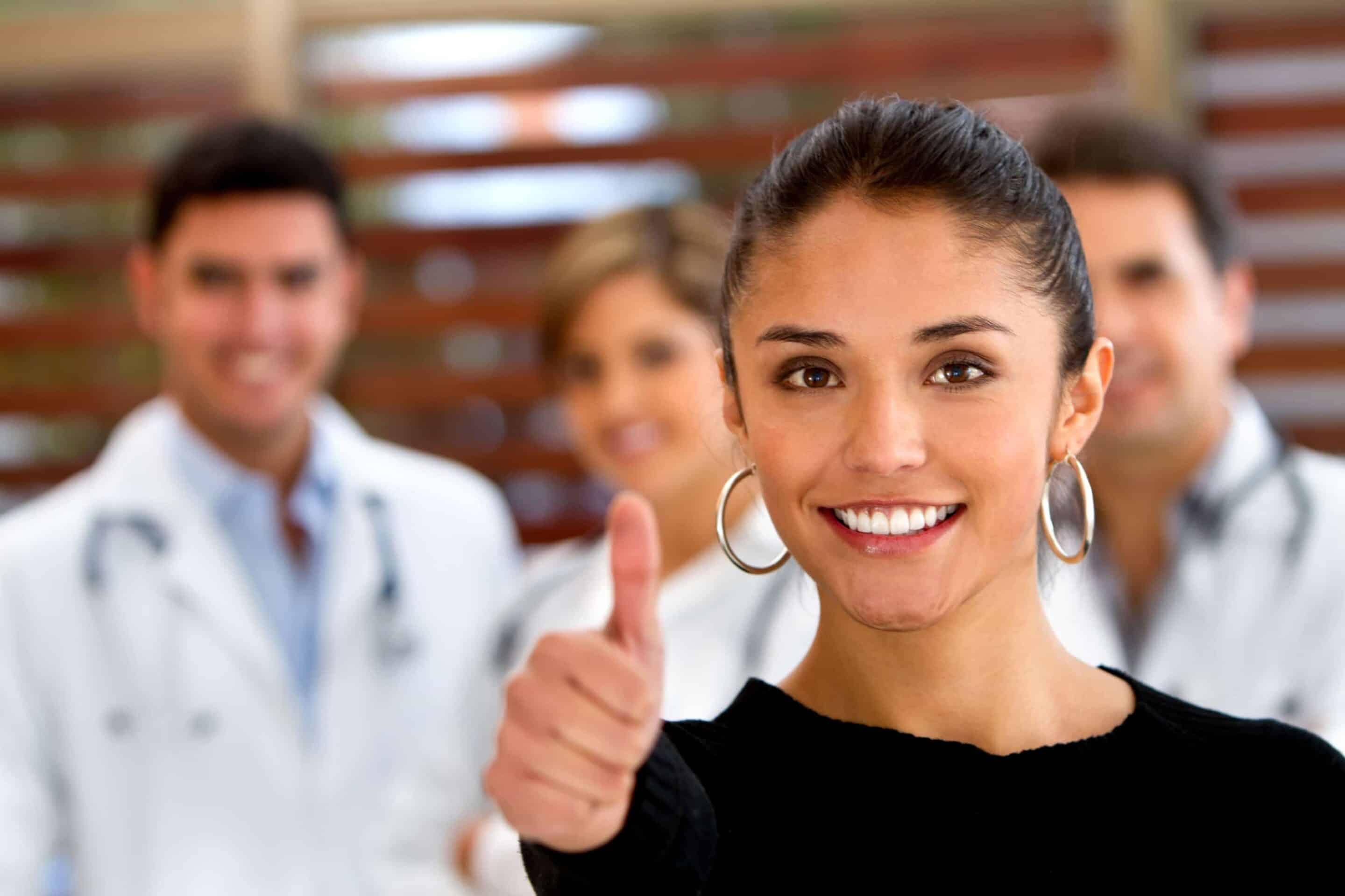 Patient with thumbs up and a group of doctors at the background